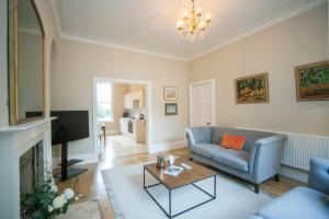 a living room with a blue couch and a tv at Garden Apartment - 11 Southcot Place in Bath