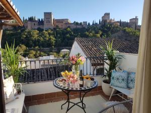 einen Balkon mit einem Tisch mit Blumen darauf in der Unterkunft Häxaris Casa Boutique by Florentia Homes in Granada