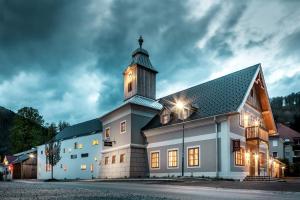 duży biały budynek z wieżą zegarową w nocy w obiekcie Hotel zum Glockenturm w mieście Marktl