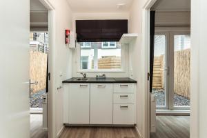 a kitchen with white cabinets and white appliances at Museumpark Apartments in Rotterdam