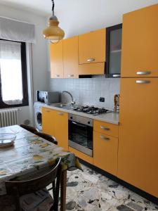 une cuisine avec des armoires orange et une table avec une table dans l'établissement CASAVACANZA CHIARA, à Gravellona Toce