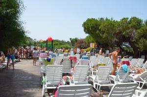 un grupo de sillas y gente en la playa en Happy Camp mobile homes in Camping Village Bella Sardinia en S'archittu Cuglieri