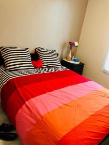 łóżko z pomarańczowym i czerwonym kocem w pokoju w obiekcie Near DISNEYLAND. Your location to enjoy holidays. w mieście Bussy-Saint-Georges