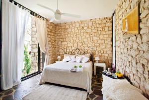 1 dormitorio con cama y pared de piedra en Stone House Modica, en Módica