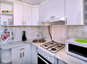 a white kitchen with a stove and a sink at KAYARAN home in Gyumri