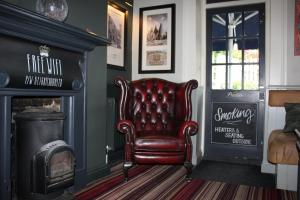 a red leather chair in a living room with a fireplace at The Prince of Wales in Reigate