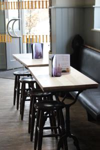 una fila de mesas de madera con sillas en un restaurante en The Prince of Wales en Reigate