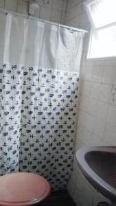 a bathroom with a shower curtain with a toilet and a sink at Casa Massaguaçu in Caraguatatuba