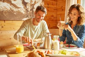 Ein Mann und eine Frau sitzen am Tisch und essen Essen. in der Unterkunft BöckLodges in Nesselwang