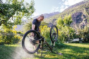 Ein Mann wäscht ein Fahrrad im Gras in der Unterkunft Garni - Hotel Rinner Julia in Latsch