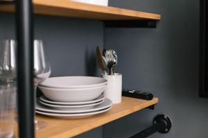a shelf with a bowl and plates and forks and knives at TG Hotel Suites Budapest in Budapest