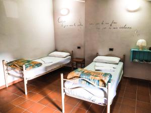 2 Betten in einem Zimmer mit Wandschreiben in der Unterkunft Ostello Palazzo Pierantoni in Foligno