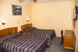 a hotel room with two beds and a desk at Hotel Roma in Durango