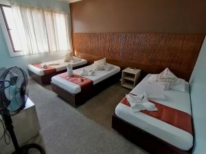 a hotel room with three beds and a fan at RB Bed and Breakfast in Kalibo