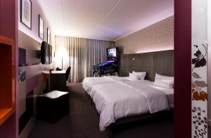 ein Hotelzimmer mit einem großen Bett und einem TV in der Unterkunft pentahotel Wiesbaden in Wiesbaden