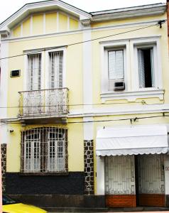 Edificio amarillo con 2 ventanas y balcón en Estúdios Deluxe São Manuel, en Río de Janeiro