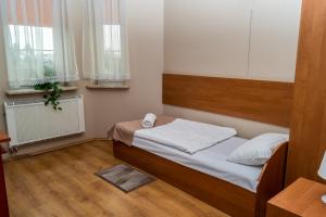 ein kleines Schlafzimmer mit einem Bett und zwei Fenstern in der Unterkunft Dworek Zacisze in Września