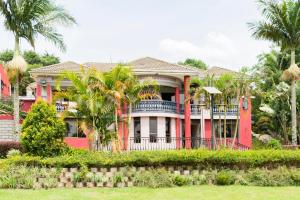 a red house with palm trees in front of it at Fort Fun City Hotel Fort Portal in Fort Portal