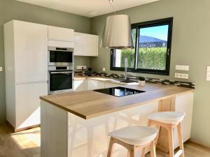 a kitchen with white cabinets and a large island with stools at Aux Peupliers de Pradian - Aurora in Bassens