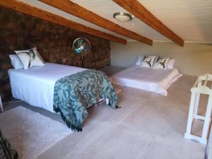 two beds in a room with wooden ceilings at Arend Cottage in Nelspruit