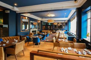 a restaurant with wooden tables and chairs and blue walls at Gleesons Townhouse Booterstown in Dublin