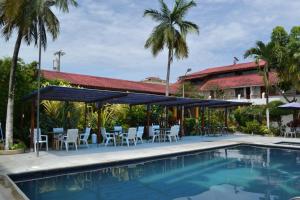 a resort with a pool and chairs and a building at Hotel Puerto Ballesta in Tonsupa