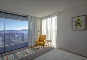 a bedroom with a bed and a chair and a large window at Encostas da Baronesa in Alijó