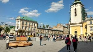 um grupo de pessoas andando em torno de uma praça da cidade com uma torre do relógio em Apartment on Filatova 10-б em Lviv