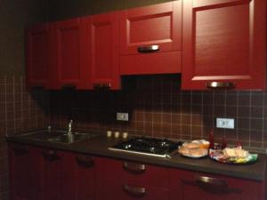 a kitchen with red cabinets and a stove and a sink at Augusta Apartment in Bibione +1 photo