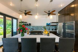 una cucina con tavolo, sedie e ventilatori a soffitto di Vivaro Roatan Beachfront a West End