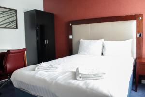a bedroom with a bed and a red wall at Heathrow Lodge in Hillingdon