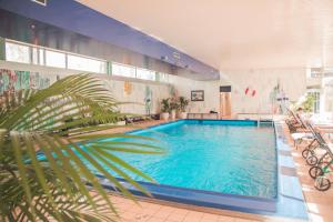 a large swimming pool in a building with a palm tree at Garden-Hotel Reinhart in Prien am Chiemsee