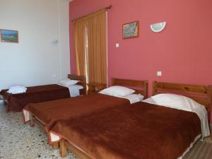 two beds in a room with red walls at Hotel Alexandrion in Kalamata