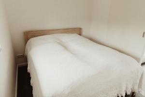 - un lit blanc dans un coin de chambre dans l'établissement Apartment Strandnüst, à Aurich