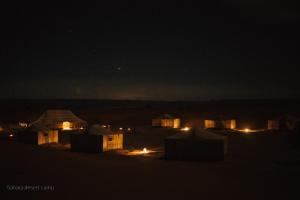 a group of tents in the desert at night at Sahara Desert Camp in Adrouine