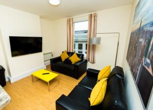 a living room with a black couch and yellow pillows at The Stay Company, Derby Central in Derby