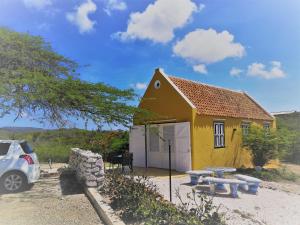 a small yellow house with a picnic table and a car at Landhuis Klein Santa Martha Boutique Hotel Restaurant. in Dorp Soto