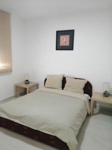 a bed in a room with two tables at Garni Hotel Plava Laguna in Ćuprija