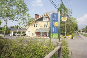 un cartel frente a una casa en una calle en Hotel Petit Riviere Karuizawa, en Karuizawa
