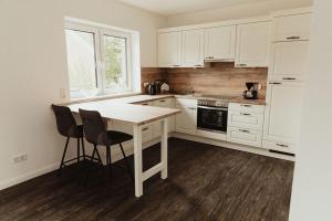 a kitchen with white cabinets and a table and chairs at Apartment Strandperle in Aurich