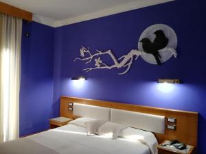 een slaapkamer met een blauwe muur met een vogel op een tak bij FILIPPONE HOTEL&RISTORANTE in Gioia dei Marsi