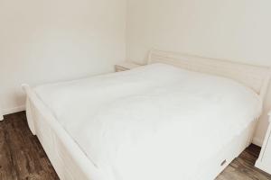 Cama blanca en habitación con pared blanca en Apartment Strandperle, en Aurich