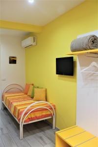Cette chambre comprend un lit et une télévision murale. dans l'établissement Anima Migrante, à Naples