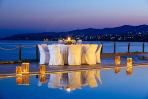 a table with white chairs and candles on top of water at Poseidon of Paros Hotel & Spa in Chrissi Akti