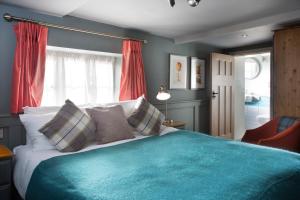a bedroom with a large bed with a blue blanket at The Ostrich Inn Colnbrook London Heathrow in Slough