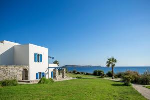 a white house with the ocean in the background at Poseidon of Paros Hotel & Spa in Chrissi Akti