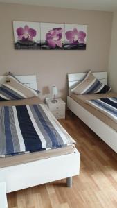 2 camas en un dormitorio con flores púrpuras en la pared en Haus Ella, en Homburg