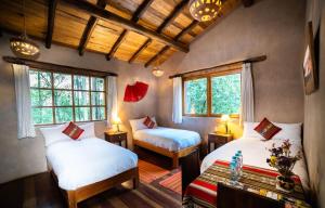 a room with two beds and two windows at Sacred Dreams Lodge in Urubamba