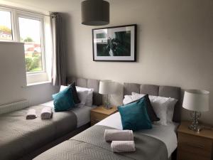 a bedroom with two beds with blue and white pillows at Mundy House in Swindon