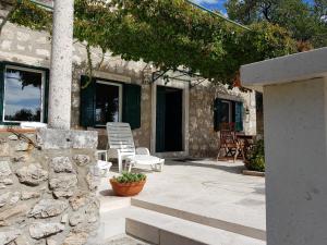 a patio with white chairs and a stone wall at Apartment Dubrava in Dubrovnik